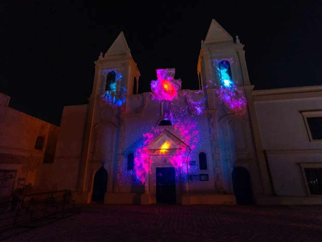 Wide view of the church facade with the particle projection over the doorway